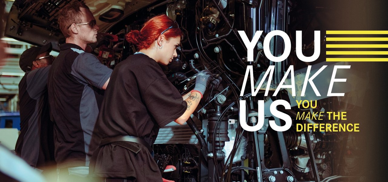 Young employees assemble parts on a truck in Daimler Truck Production - teamwork and commitment in a holiday job. Text in the picture: ‘You make us - You make the difference.’